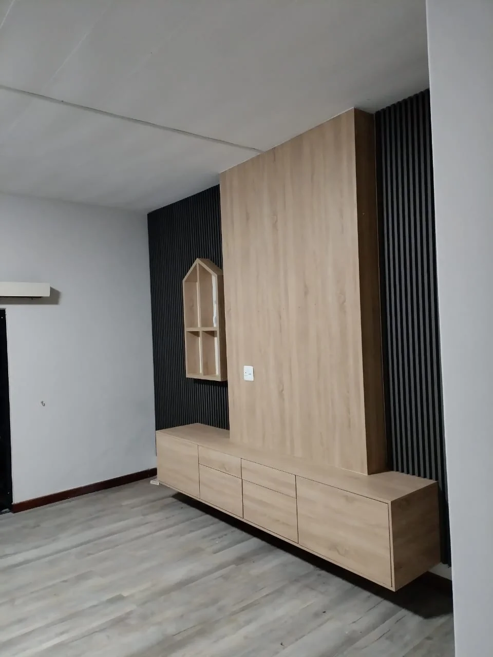 Wood-effect media unit and slatted feature wall by Z J Ceiling and Kitchen Masters
